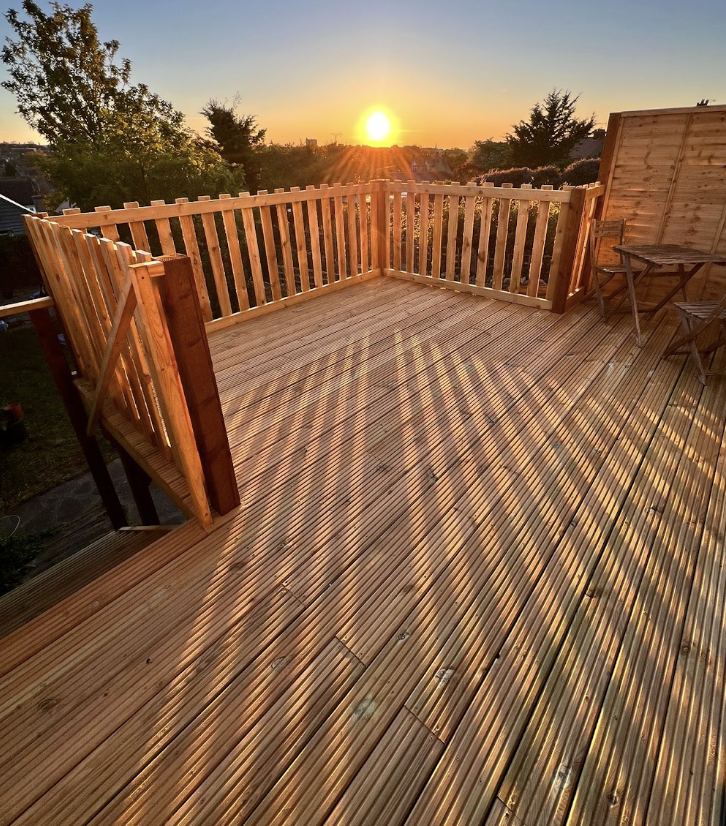 Wesley, owner of Lawn Ranger Landscapes, on a completed decking job at sunset